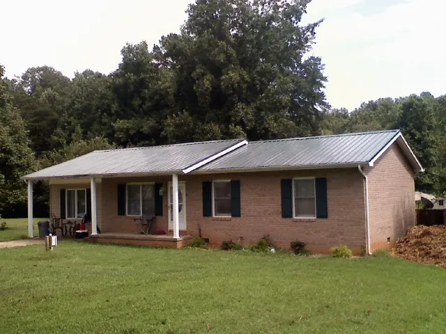 Gray metal roof on a brick ranch house with a side carport in Englewood