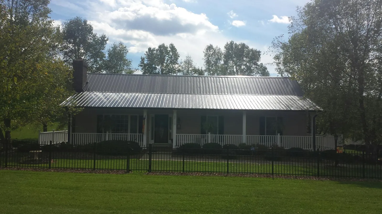 Gray metal roof on a brick ranch with a full width front porch — Gutter Guard Installation work by our crew in Englewood
